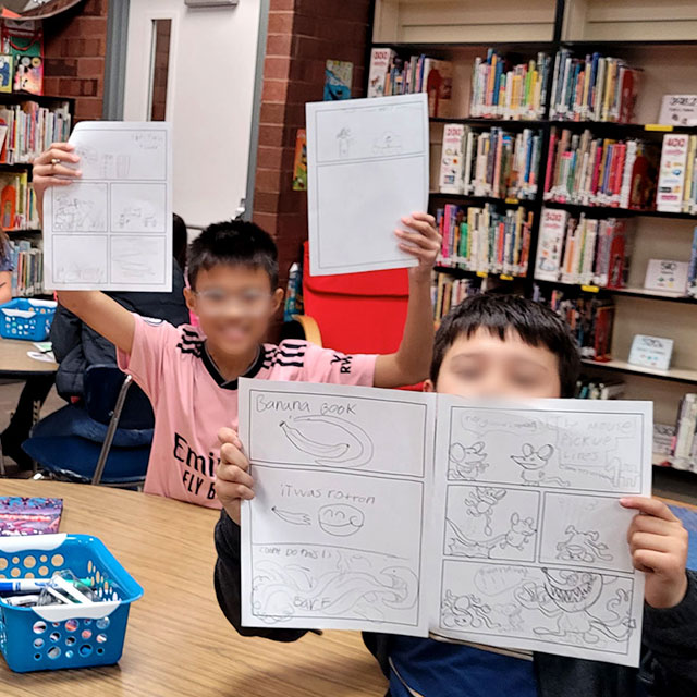 Photo of proud children holding comics they made during a visit