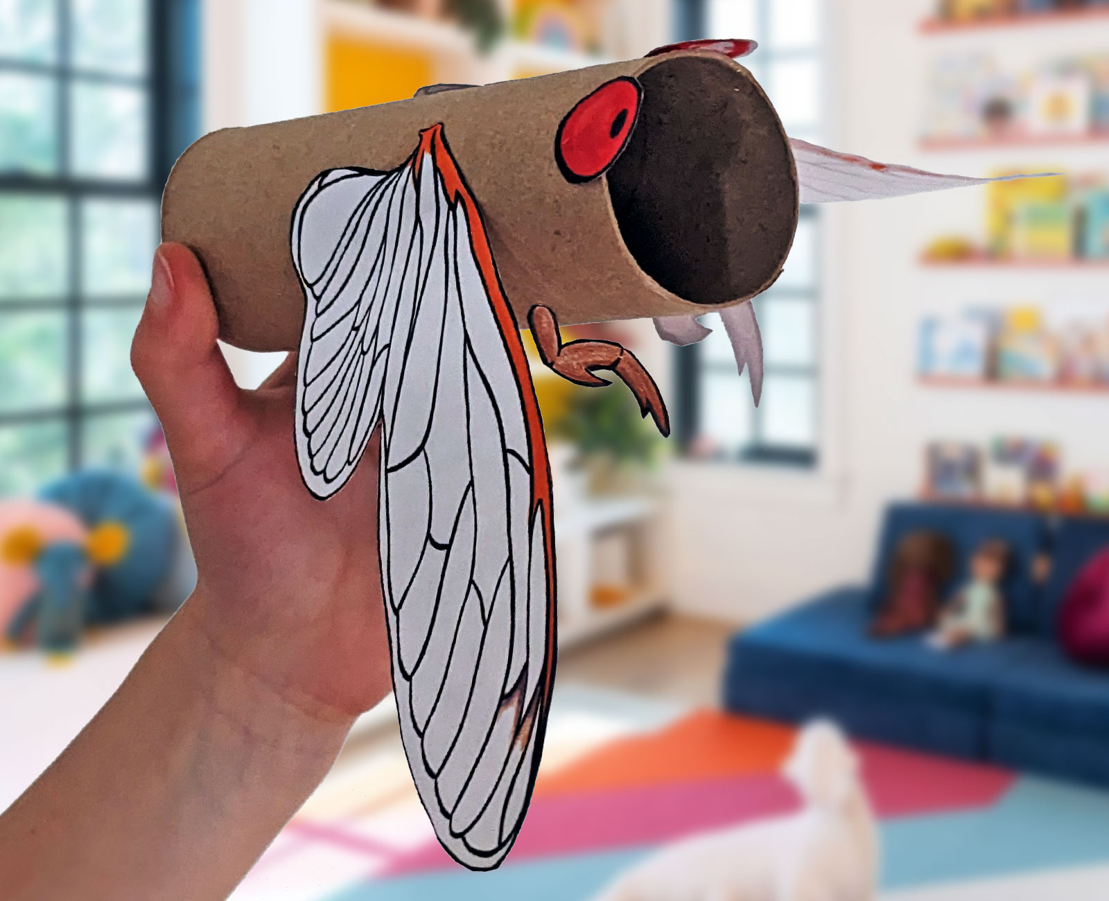 A photo of a cicada craft made from a printable and a toilet paper roll